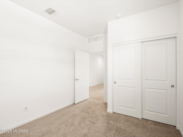 unfurnished bedroom with light carpet, a closet, and baseboards