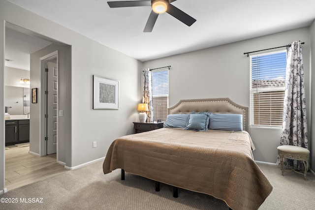 bedroom featuring baseboards, connected bathroom, and light colored carpet