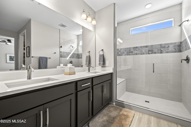 bathroom featuring double vanity, a stall shower, visible vents, and a sink