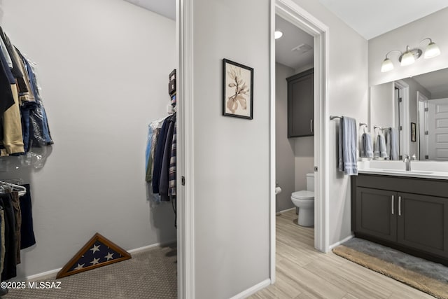 bathroom featuring toilet, wood finished floors, vanity, and baseboards