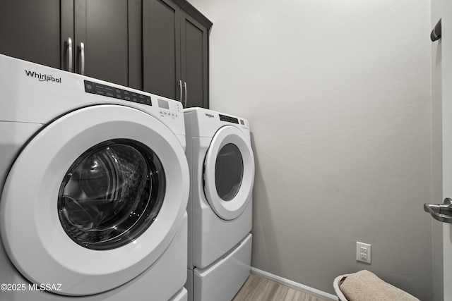 laundry area featuring cabinet space, baseboards, light wood finished floors, and washer and dryer