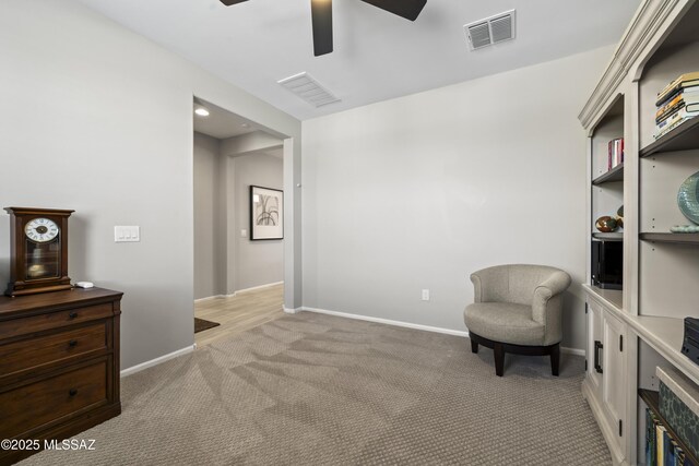 office area with a ceiling fan, visible vents, and light carpet