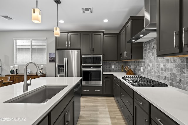 kitchen featuring a sink, appliances with stainless steel finishes, wall chimney range hood, and visible vents