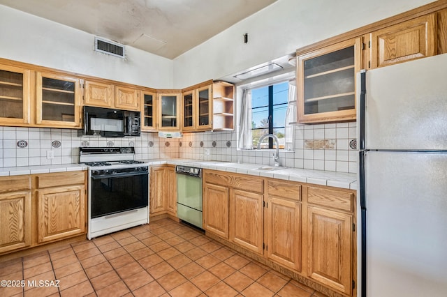 kitchen featuring black microwave, dishwashing machine, a sink, range with gas stovetop, and freestanding refrigerator