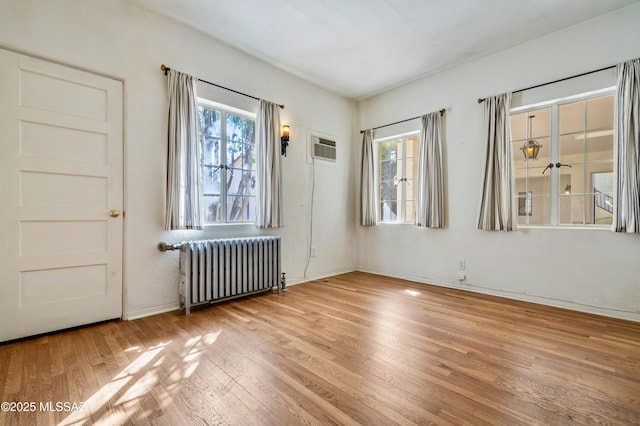 spare room with radiator, a healthy amount of sunlight, and light wood-style flooring