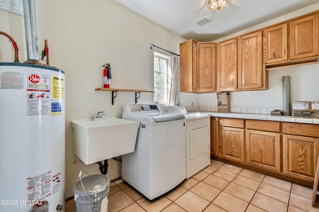 washroom featuring a sink, visible vents, water heater, cabinet space, and washer and clothes dryer