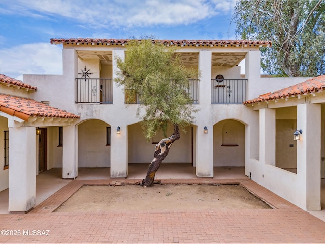 mediterranean / spanish home featuring a patio area, a balcony, and stucco siding