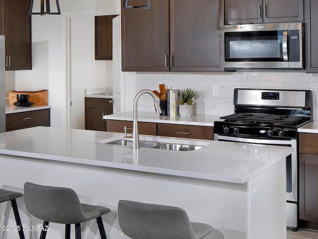 kitchen with a sink, a kitchen breakfast bar, appliances with stainless steel finishes, and dark brown cabinets