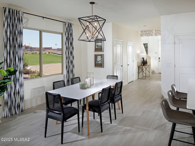 dining room with light wood-type flooring and a notable chandelier