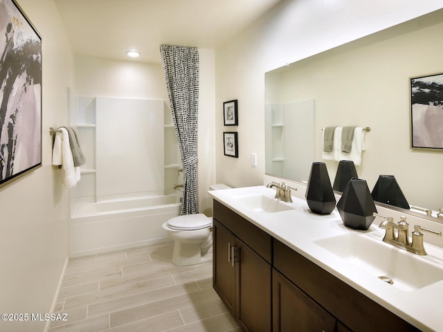 full bathroom featuring double vanity, toilet, wood tiled floor, and a sink