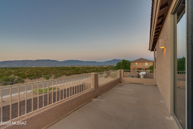 patio terrace at dusk featuring a balcony and a mountain view