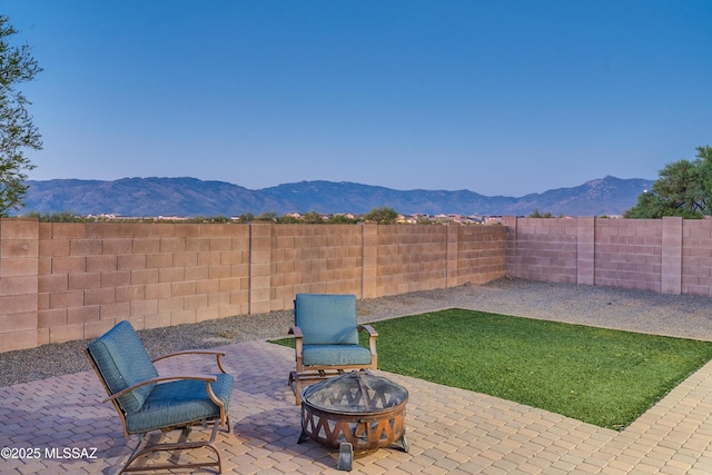 view of patio / terrace with an outdoor fire pit, a fenced backyard, and a mountain view