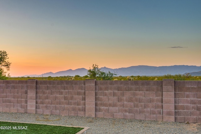 yard at dusk featuring fence and a mountain view