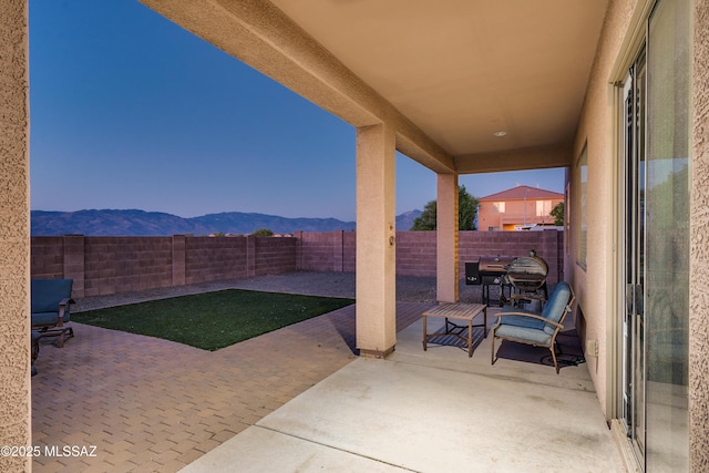 view of patio featuring a fenced backyard, a grill, and a mountain view