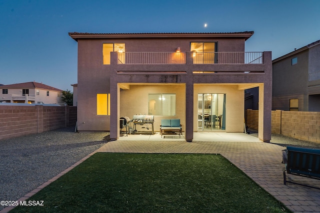 rear view of property featuring a patio area, a fenced backyard, a balcony, and stucco siding