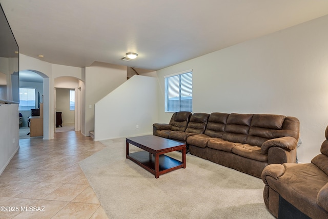 living area featuring arched walkways, visible vents, and light tile patterned floors