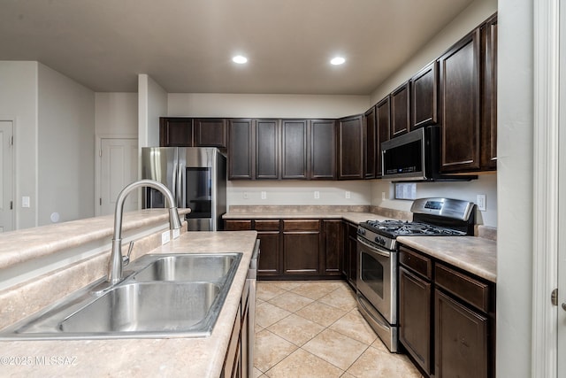 kitchen with stainless steel appliances, light countertops, a sink, and dark brown cabinetry