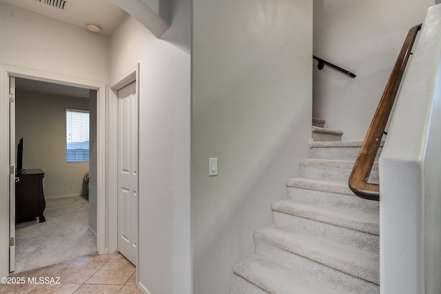 stairway featuring visible vents, baseboards, carpet flooring, and tile patterned floors