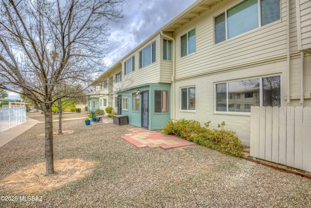 rear view of property featuring brick siding, fence, and a patio