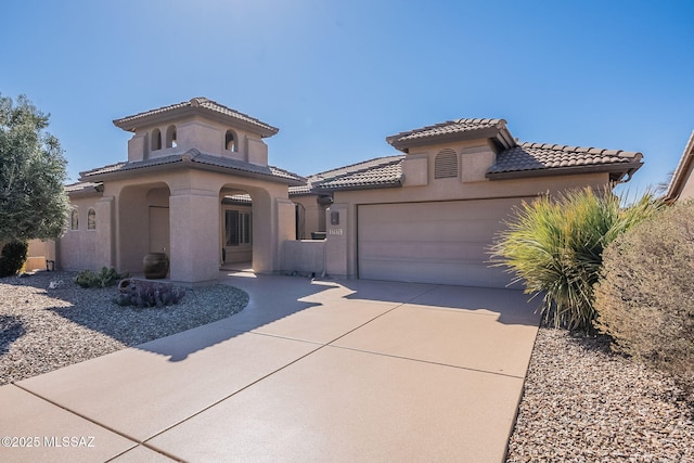 mediterranean / spanish house with concrete driveway, an attached garage, a tile roof, and stucco siding