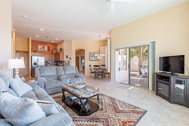 living area featuring ceiling fan with notable chandelier, arched walkways, recessed lighting, and light tile patterned floors