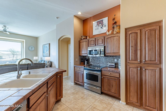 kitchen with tile countertops, tasteful backsplash, stainless steel appliances, and a sink