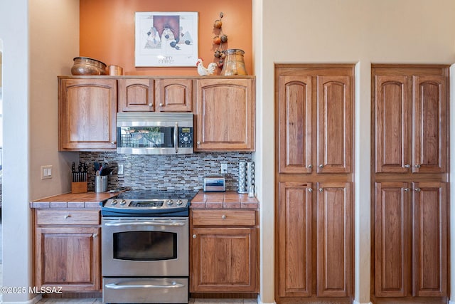 kitchen with tile countertops, tasteful backsplash, and appliances with stainless steel finishes