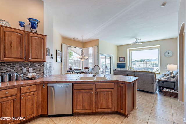 kitchen with tile countertops, a sink, open floor plan, dishwasher, and brown cabinetry