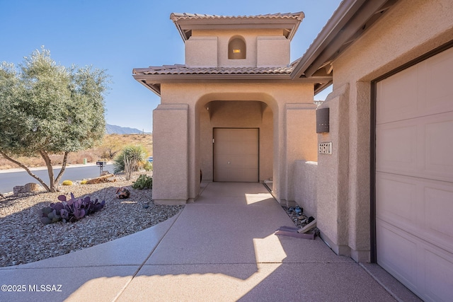 property entrance with a tile roof, a mountain view, and stucco siding