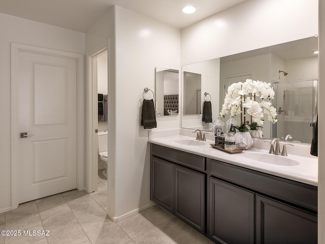 bathroom with double vanity, toilet, a stall shower, and a sink