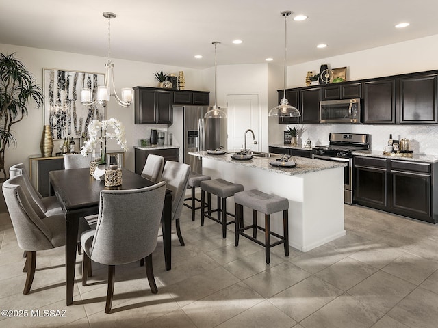 kitchen with a kitchen bar, pendant lighting, a sink, stainless steel appliances, and decorative backsplash