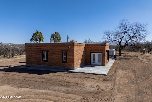 back of property featuring brick siding, a patio area, and french doors