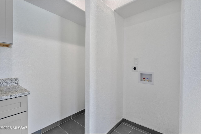 laundry area featuring dark tile patterned flooring, washer hookup, baseboards, cabinet space, and electric dryer hookup