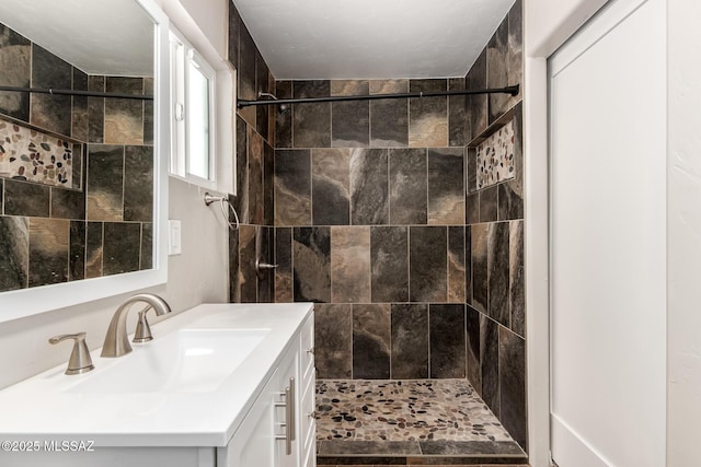 full bathroom featuring a tile shower and vanity