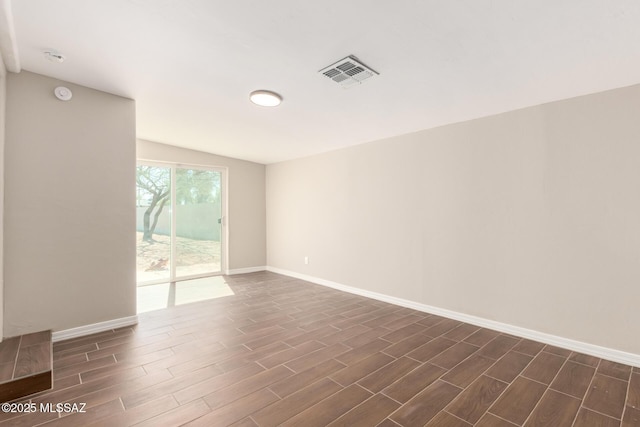 unfurnished room featuring baseboards, visible vents, and wood finish floors