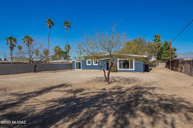 rear view of house with fence and stucco siding