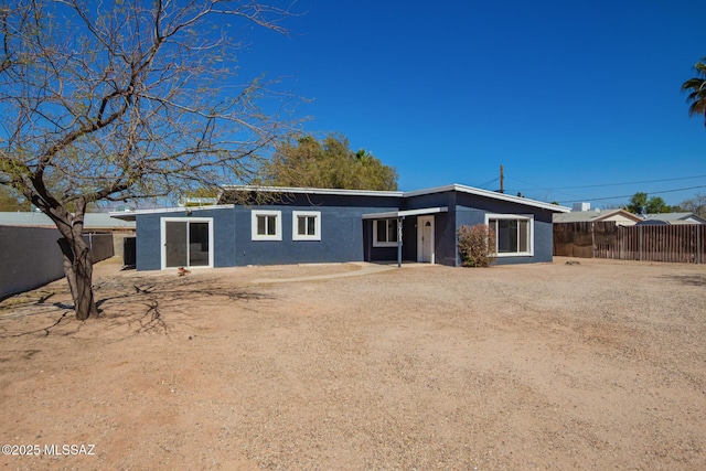 rear view of property with fence and stucco siding