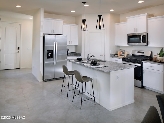 kitchen with a center island with sink, appliances with stainless steel finishes, white cabinetry, and a kitchen breakfast bar