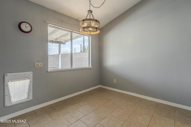 spare room featuring light tile patterned floors, baseboards, and a chandelier