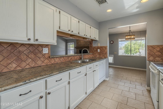 kitchen with a sink, white cabinetry, baseboards, white appliances, and visible vents