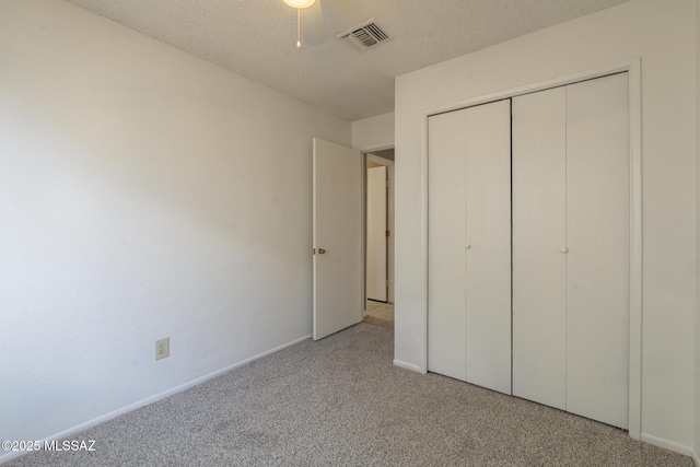 unfurnished bedroom with baseboards, a textured ceiling, visible vents, light carpet, and a closet