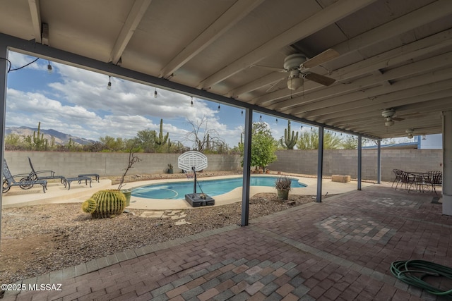 view of pool with a fenced in pool, a fenced backyard, ceiling fan, a mountain view, and a patio area