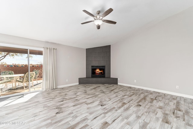 unfurnished living room with lofted ceiling, a ceiling fan, wood finished floors, baseboards, and a tile fireplace