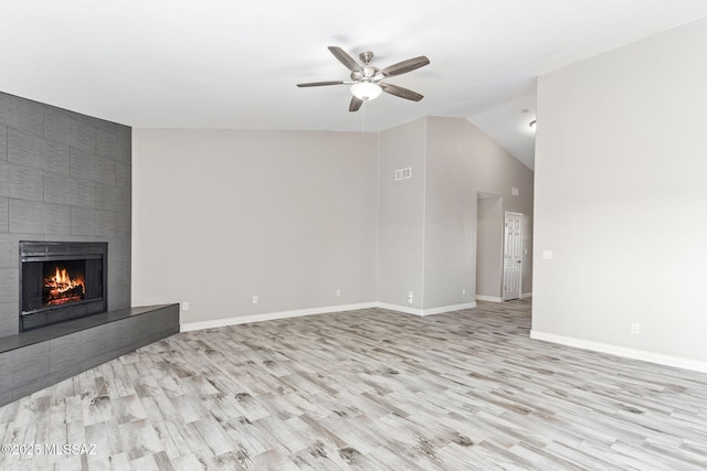 unfurnished living room featuring vaulted ceiling, a large fireplace, baseboards, and wood finished floors