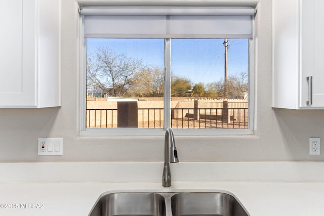 interior details with light countertops, white cabinets, and a sink