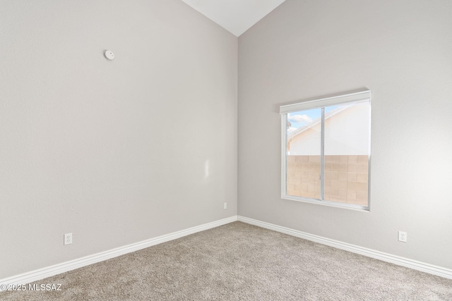 carpeted spare room with vaulted ceiling and baseboards