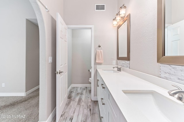 full bath featuring double vanity, visible vents, toilet, and a sink