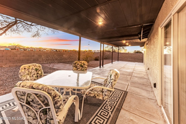 patio terrace at dusk featuring a fenced backyard