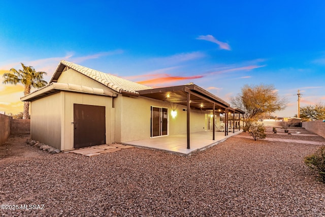 rear view of property featuring a tiled roof, a patio area, a fenced backyard, and stucco siding