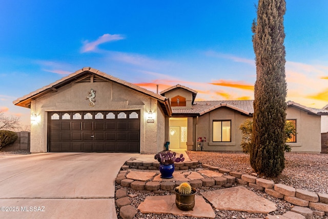 view of front of home with a tile roof, concrete driveway, a garage, and stucco siding